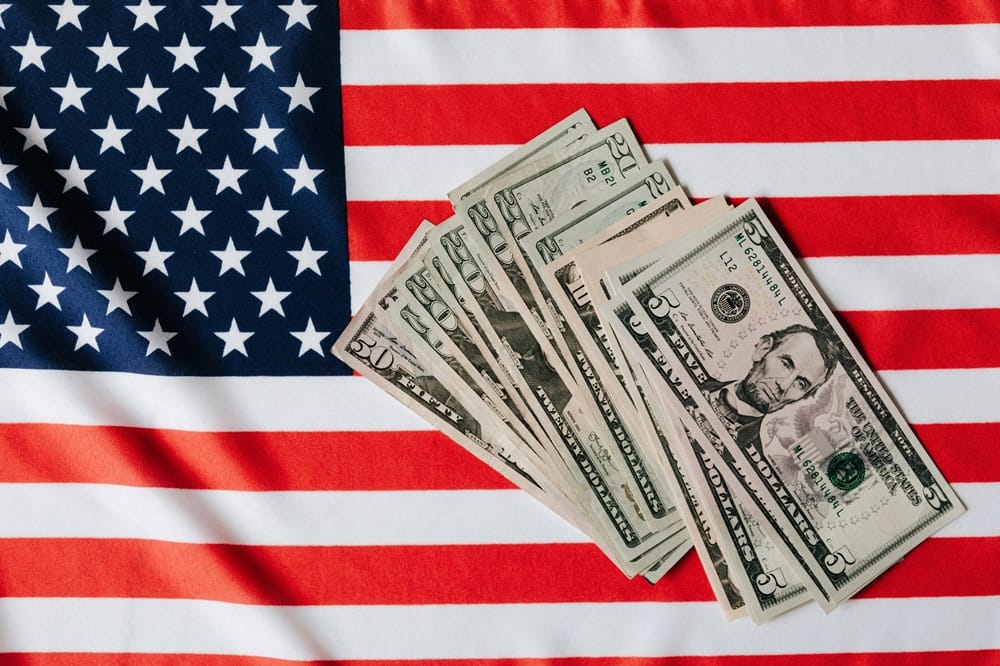 Dolares encima de la bandera de los EEUU para hablar del flujo de caja constante en las inversiones en bienes raices